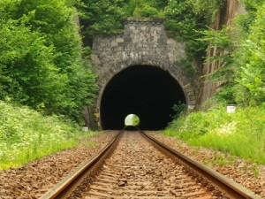 View into old railway tunnel, rusty rails and oiled sleepers.